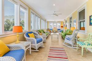 a living room with chairs and couches and windows at Tenth Street Retreat in Tybee Island