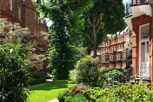 a garden with bushes and trees and buildings at The Franklin London - Starhotels Collezione in London