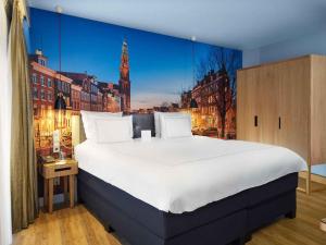 a bedroom with a large bed with a view of a city at Swissôtel Amsterdam in Amsterdam