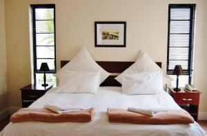 a bedroom with a white bed with two towels on it at Fourteenth Green Guest Lodge in East London