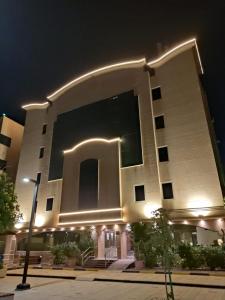 a large white building with a lit up building at 2 Bed Room near GULF DELMON in Al Mubārakīyah