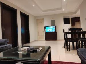 a living room with a table and a tv at 2 Bed Room near GULF DELMON in Al Mubārakīyah