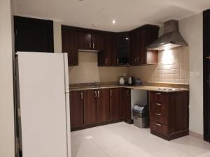 a kitchen with wooden cabinets and a refrigerator at 2 Bed Room near GULF DELMON in Al Mubārakīyah