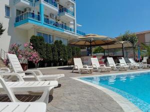 a group of chairs and an umbrella next to a swimming pool at Елегантно Студио В18 в комплекс Одисей, Несебър in Burgas City