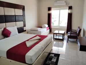 a bedroom with a bed and a chair and a window at Hotel New Rajdarshan in Madikeri