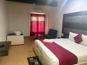 a bedroom with a bed and a chair and a window at Hotel New Rajdarshan in Madikeri