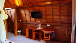 a room with a wooden wall with a table and a tv at Villa Lumbung Sidemen in Sidemen