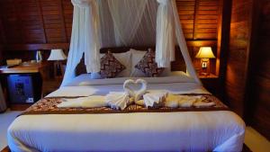 a bedroom with a bed with two swans on it at Villa Lumbung Sidemen in Sidemen +33 photos