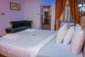 a bedroom with a large bed with white sheets and pillows at D&G Hotels & Suites in Agege