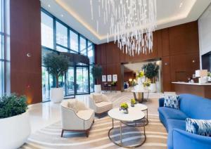 a lobby with a blue couch and chairs and a chandelier at Address Dubai Opera Residences in Dubai