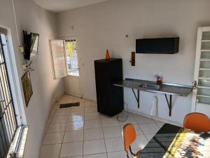 a kitchen with a black refrigerator and a table and chairs at Sobrado Mãezinha Aparecida in Aparecida