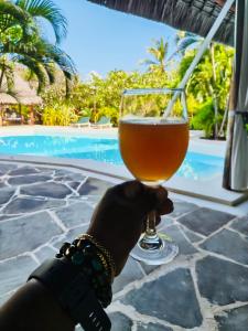 a person holding a glass of beer next to a pool at Casa Madro in Malindi
