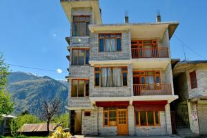 a tall building with windows and mountains in the background at Sarthak Home Stay, Beautiful Valley view of Mountain in Jagatsukh