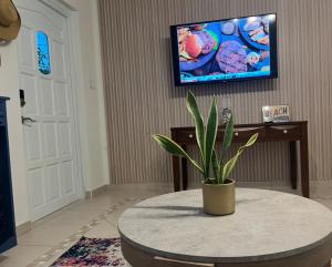 Una sala de estar con una mesa y un televisor en una pared. en Villa Fina Aruba, en Palm-Eagle Beach