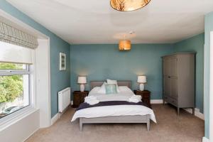 a bedroom with a bed with blue walls and a window at Baie Mooar House, Boutique B&B in Ramsey