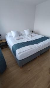 ein großes Bett mit weißer Bettwäsche und einer blauen Decke in der Unterkunft Apartament I Na Słonku in Dzierzgoń