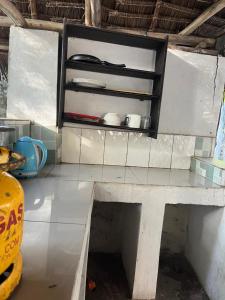 a kitchen with a bench and a shelf with utensils at Olga Beach Nungwi in Nungwi