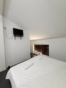 a bedroom with a white bed with a tv on the wall at Restaurant-Motel Khan Krum in Kamchiya