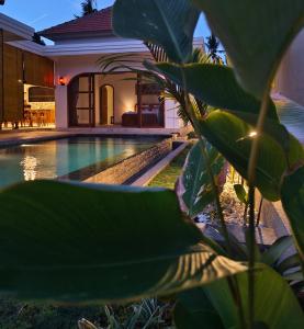 a villa with a swimming pool in front of a house at Bukti Garden Villas in Bukti