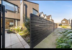 a wooden fence in front of a house at The Petone Beauty - Flash, Beachside in Lower Hutt