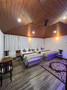 a bedroom with three beds and a wooden ceiling at House of Raj in Madikeri
