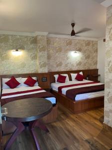 a hotel room with two beds and a table at House of Raj in Madikeri