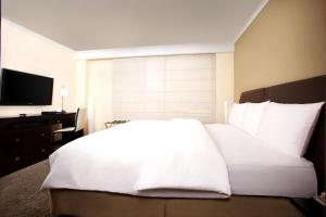 Un dormitorio con una cama blanca y un televisor. en Swissotel Quito, en Quito