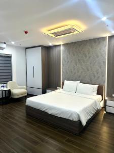 a bedroom with a large white bed and a chair at Elegant Hotel in Hanoi