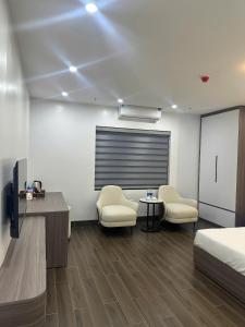 a bedroom with a bed and two chairs and a table at Elegant Hotel in Hanoi +4 photos