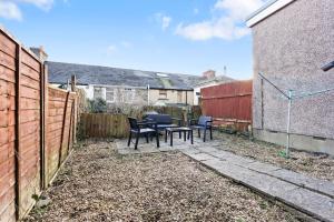 a patio with chairs and a table in a backyard at Hillview Escape - Group-Friendly Comfort in Abertillery