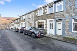 two cars parked in front of a brick building at Haven on the Hill - FREE Parking & Great for Groups in Abertillery