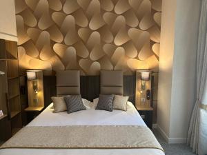 a bedroom with a large bed with a wooden wall at HOTEL ARVERNA VICHY - ClT'HOTEL in Vichy