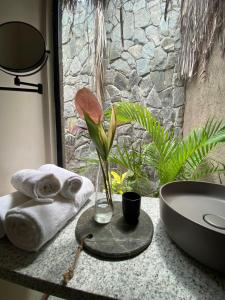 a bathroom with a sink and a vase with a flower at Evva Pousada in Pôrto de Pedras