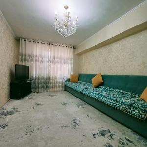 a living room with a green couch and a chandelier at South Gate of Bishkek in Bishkek