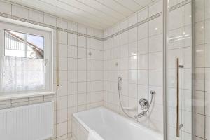 a white bathroom with a tub and a window at EG Apartment - WLAN - Terrasse - Parkplatz in Buchenberg +17 photos
