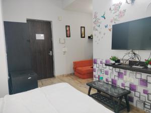 Pearl suites at omaxe eternity near prem mandir في فريندافان: غرفة بسرير وتلفزيون وأريكة
