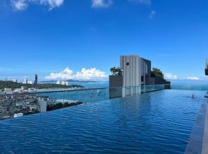 Pattaya the base condo في باتايا سنترال: مسبح لا نهاية له على رأس مبنى مع مدينة