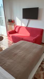 ein Wohnzimmer mit einem roten Sofa und einem Fernseher in der Unterkunft Novegro Linate 101 in Linate
