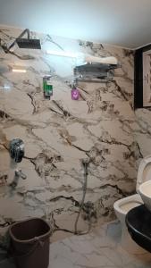 a bathroom with a marble wall with a toilet at Marquis Luxe Guest House in Kolkata