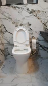 a white toilet in a bathroom with a marble wall at Marquis Luxe Guest House in Kolkata