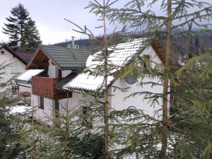 a white house with snow on the roof at Domek na Malinowej in Szczyrk +3 photos