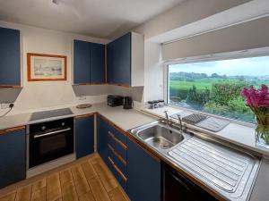 a kitchen with a sink and a large window at Airdside Cottage in Crossmichael
