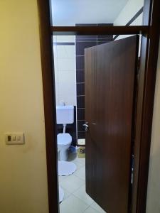 a bathroom with a toilet and a wooden door at Appartment in the center of town Fushe Kosova in Kosovo in Kosovo Polje