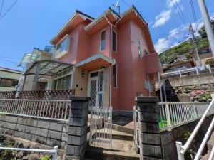 a pink house with a white fence at Minpaku ROADHOUSE - Vacation STAY 20160v in Nagasaki