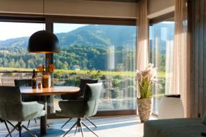 a room with a table and chairs and a large window at Stilvolles Ferienhaus Südsteiermark ruhige Lage top Aussicht & E-Ladestation in Eibiswald