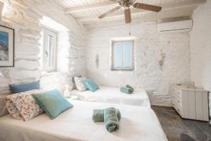 two beds in a white room with stone walls at Villa Néréides in Koundouros +29 photos