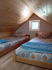 two beds in a attic bedroom with wooden ceilings at Vila Tutić Apartman 1 i Apartman 2 in Mitrovac