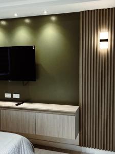 een slaapkamer met een flatscreen-tv aan de muur bij Sequoia Suites at Azure North in San Fernando