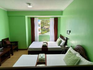 a green room with two beds and a window at Albergo Hotel - Studio Condo Unit - Baguio Transient in Baguio