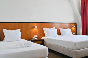 two beds in a hotel room with white pillows at Hotel Bagoeira in Barcelos